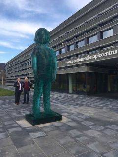 Het ‘reuzenkind’ voor het protonentherapiecentrum van het UMCG, met daarachter bestuursvoorzitter Jos Aartsen (links) en kunstenaar Herman Lamers.